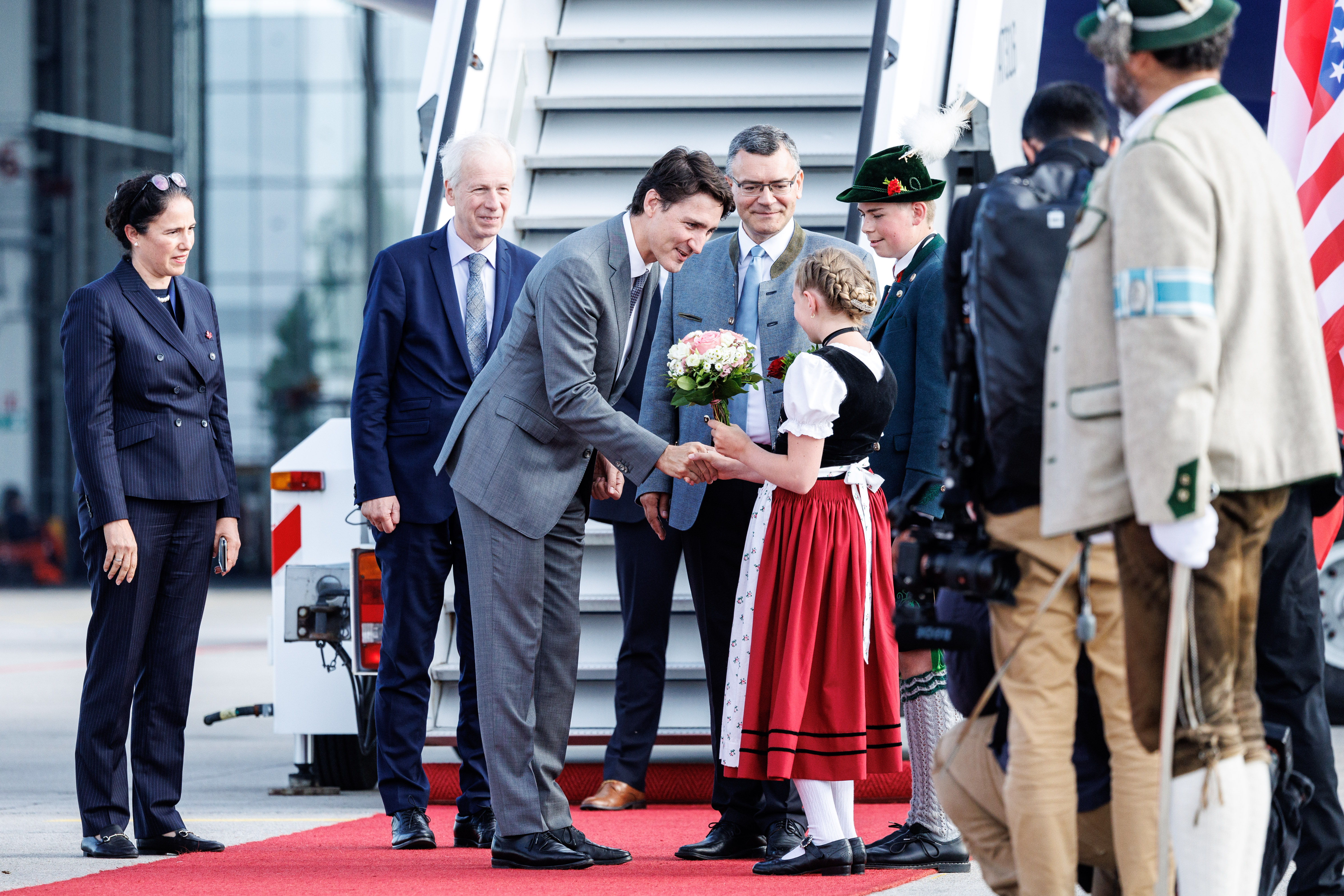 Justin Trudeau (Premierminister Kanada), wird bei seiner Ankunft am Flughafen München von einem Mädchen in Tracht begrüßt.