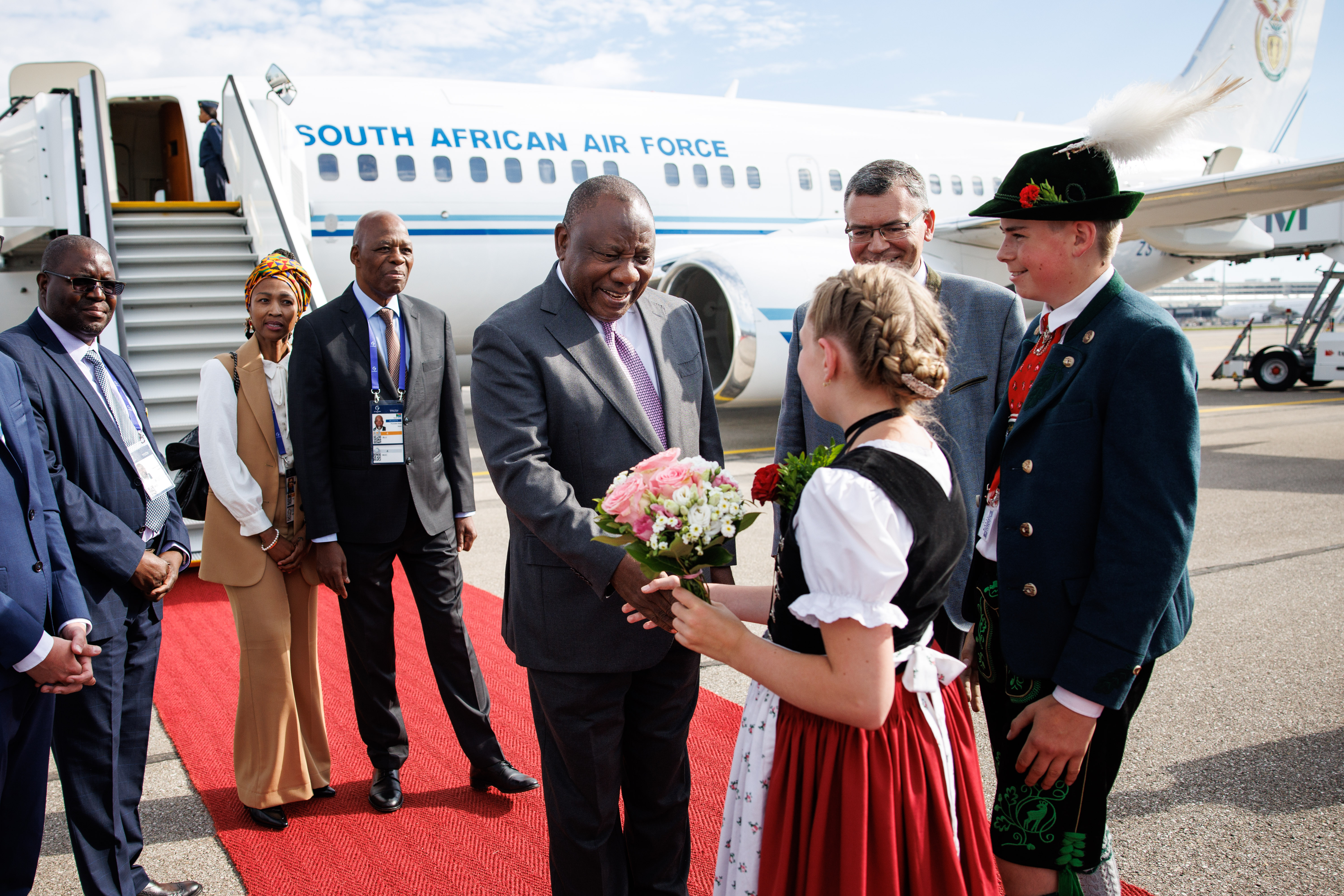 Arrival of Cyril Ramaphosa (President of South Africa) at Munich Airport and welcome by Florian Herrmann, Head of the Bavarian State Chancellery, and a girl wearing traditional costume.