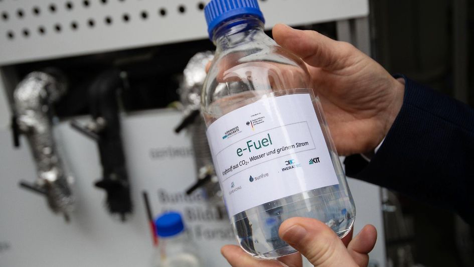 Roland Dittmeyer, Leiter des Instituts für Mikroverfahrenstechnik am Karlsruher Institut für Technologie, hält eine Flasche mit e-Fuel in den Händen.