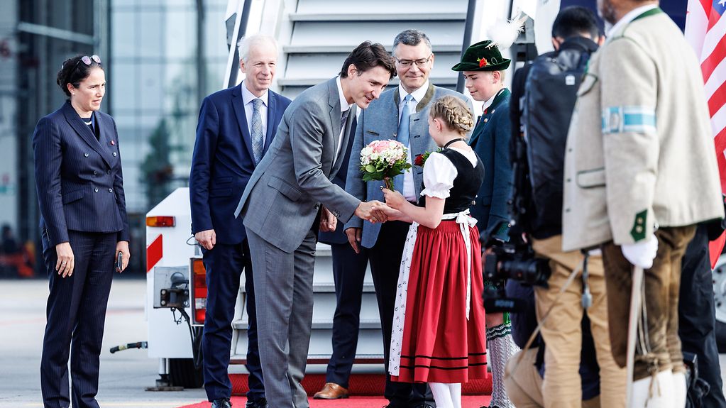 Justin Trudeau (Premierminister Kanada), wird bei seiner Ankunft am Flughafen München von einem Mädchen in Tracht begrüßt.