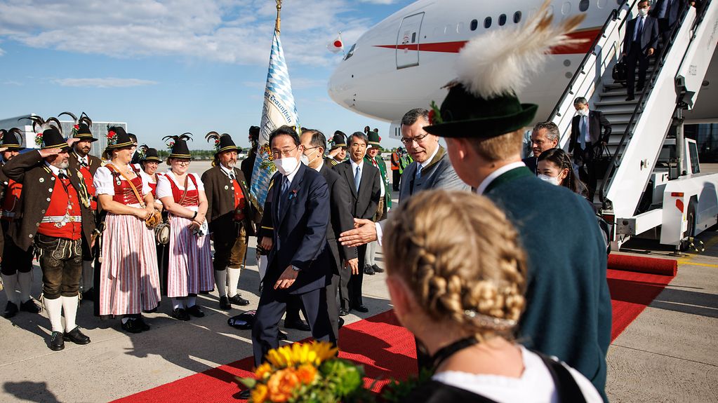 Arrival of Fumio Kishida (Prime Minister of Japan) at Munich Airport, welcome by Florian Herrmann, Head of the Bavarian State Chancellery, and members of a group wearing traditional Bavarian costume.