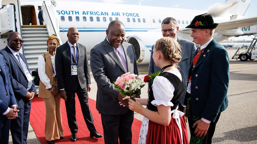 Arrival of Cyril Ramaphosa (President of South Africa) at Munich Airport and welcome by Florian Herrmann, Head of the Bavarian State Chancellery, and a girl wearing traditional costume.