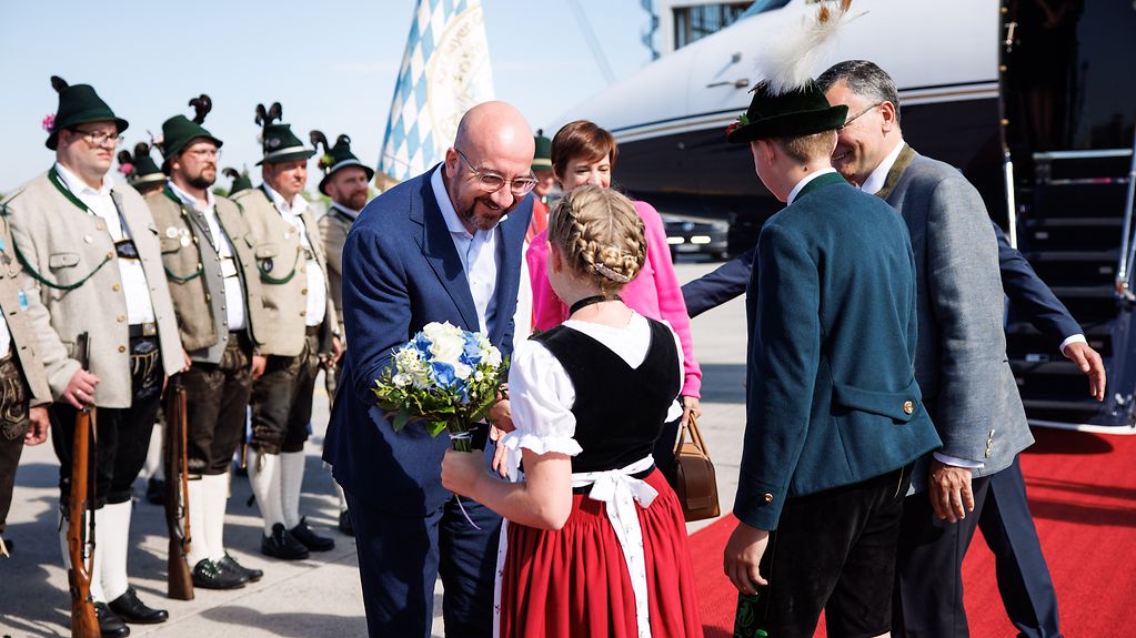 Ankunft von Charles Michel (Präsident Europäischer Rat) und seiner Frau Amélie Derbaudrenghien auf dem Flughafen München und Begrüßung durch ein Mädchen in Tracht.