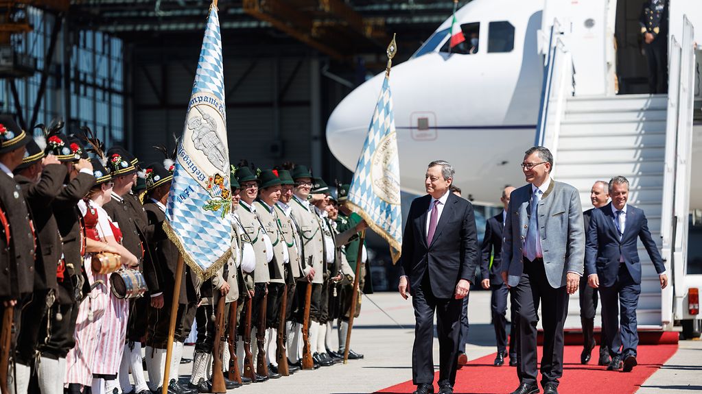 Mario Draghi (Prime Minister of Italy) being welcomed by Florian Herrmann and a group wearing traditional Bavarian costume.