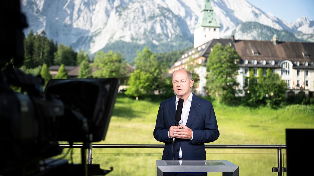 Federal Chancellor Olaf Scholz speaks on German television’s ZDF-Morgenmagazin. In the background we see Schloss Elmau.