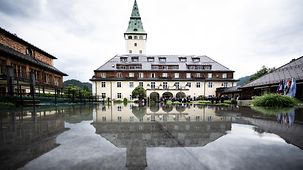 Schloss Elmau reflected in a body of water.