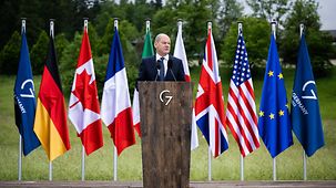 Bundeskanzler Scholz am Rednerpult vor den G7-Fahnen.