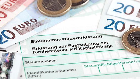 Formular zur Einkommenssteuererklärung mit Scheinen und Münzen.