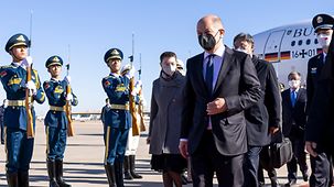 Bundeskanzler Olaf Scholz geht bei der Begrüßung auf dem Flughafen durch ein chinesisches Ehrenspalier.
